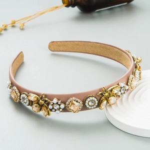 Close-up of headband with gold bees, champagne crystals and pearls on satin