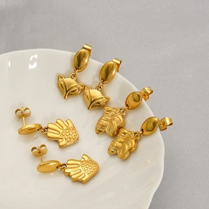 Ensemble de boucles d'oreilles renard et abeille en acier titane sur plat céramique