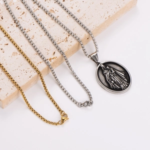 Religious pendant necklace with stainless steel box chains on a stone display
