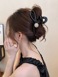 Elegant large black cross hair claw clip with pearl accents shown on a classic updo