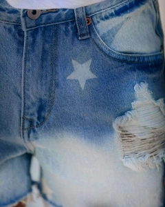 Detailopname van lichtblauwe denim short met sterrenprint en gescheurde texturen