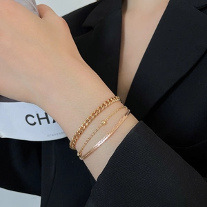 Close-up of golden three-piece bracelet set including snake, cuban, and bead chains