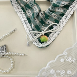 Detail of green plaid headband with white lace trim and a small lime fruit charm