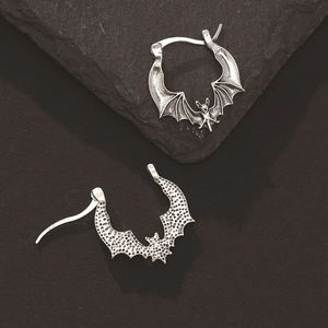 Close-up of vintage silver bat stud earrings with intricate gothic wings and texture