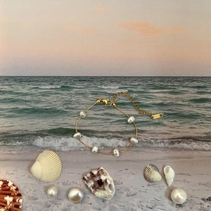 Detailed view of an 18k gold stainless steel bracelet with irregular baroque pearls and shells