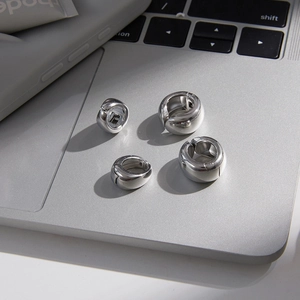 Polished silver stainless steel hoop earring set on a modern laptop workspace