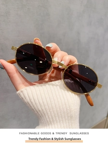 Primer plano detallado de gafas de sol ovaladas retro con montura dorada y patas de madera