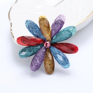 Detailed macro view of acrylic flower brooch with colorful textured petals and pink gemstone