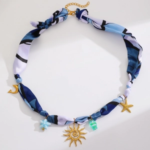 Détail du collier ruban en soie imprimé avec breloques dorées soleil et étoile de mer
