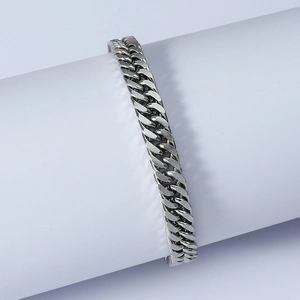 Polished silver cuban link chain bracelet displayed on a cylindrical white jewelry stand