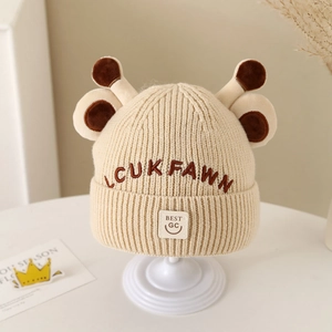 Detailed knit texture of beige giraffe-style beanie with soft plush antlers and embroidery