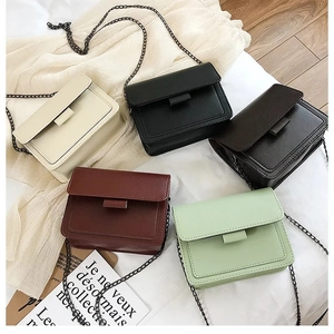 Flat lay of small square handbags in beige black burgundy and green with metal chains