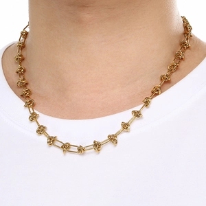 Detail of 18K gold-plated stainless steel knotted chain necklace worn by a model