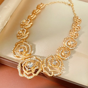 Detailed close-up of a gold rose-shaped pendant necklace with clear sparkling crystals