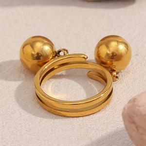 Macro shot of gold double sphere ring with polished metal balls on textured stone