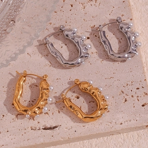 Detail of U-shaped gold and silver earrings with lava texture and small white pearls