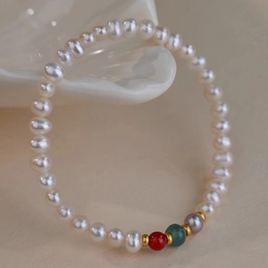 Close-up of fresh water pearls with red and green agate beads on ceramic plate
