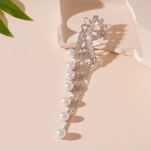 Détail macro du clip d'oreille argenté avec glands en cristal et perles de fantaisie