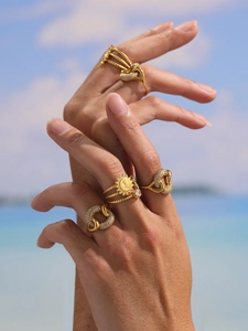 Detail of bohemian gold rings set with sun and sunburst motifs against a sky background