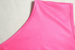 Dettaglio ravvicinato della doppia cucitura su un elegante abito rosa acceso con spalla scoperta