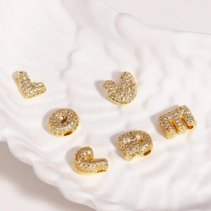 Gros plan de pendentifs lettres L O V E M S dorés en cuivre sertis de zircons