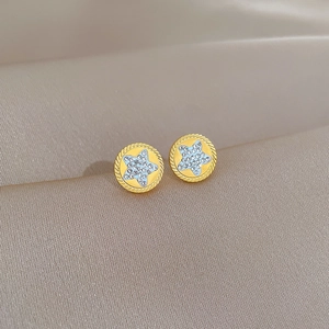 Macro shot of gold-plated star stud earrings with blue crystals on silk fabric