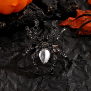 Détail d'une bague araignée gothique avec pierres noires sur fond de citrouille