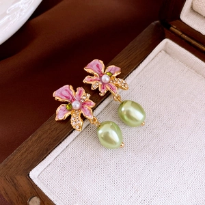 Macro view of vintage pink enamel flower earrings with baroque pearls and green crystals