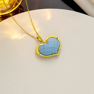Elegant gold heart pendant necklace with faceted blue stone on a display stand