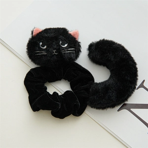 Detail of plush black cat scrunchie with 3D ears and embroidered eyes on white background