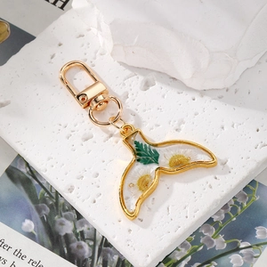 Macro detail of fish tail resin pendant with real dried flowers and golden metal edge