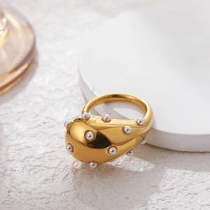 Macro shot of gold plated water drop ring featuring inlaid white pearls on polished metal