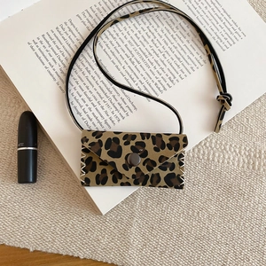 Close-up of leopard print mini bag pendant with metallic snap button on art book