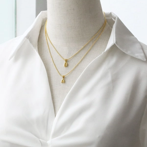 Polished gold initial necklaces with A and B pendants on a model wearing a white shirt