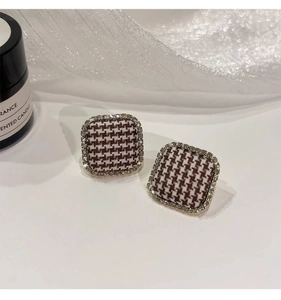 Macro detail of square houndstooth fabric earrings with sparkling zircon borders