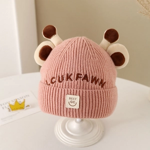 Detailed knit texture of pink kids' beanie with cute deer antlers and LCUKFAWN embroidery