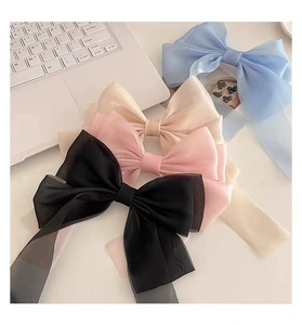 Detail of four colorful sheer organza bow hair clips with long streamers on a desk