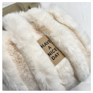 Close-up of soft white faux fur texture with a brown leather label saying Have a Nice Day