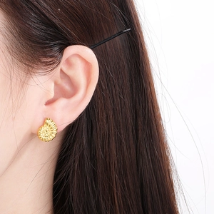 Close-up of model wearing gold conch shell earrings made of polished stainless steel