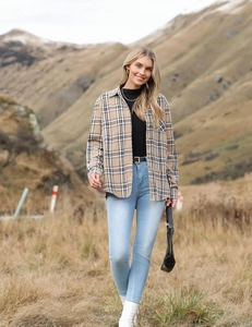 Outdoor fashion shot of khaki plaid button-down shirt styled with light blue skinny jeans