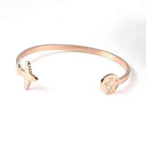 Detailed view of rose gold stainless steel cuff bracelet with airplane and map charms