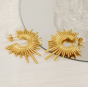 Detailed view of gold sunburst geometric earrings reflecting on a mirror surface