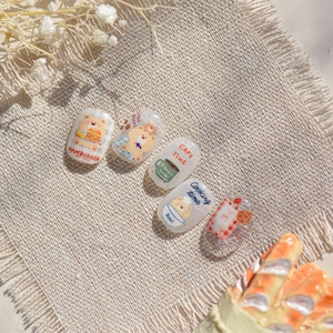 Macro view of cartoon bear and coffee themed embossed nail art stickers on linen