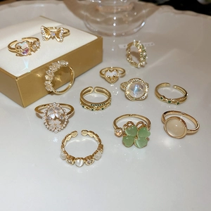 Detailed close-up of golden adjustable rings with opal, pearls, and crystals in a box