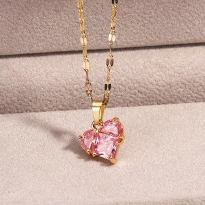 Detail of gold necklace featuring a faceted pink heart gemstone on a beige velvet surface