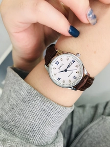 Detail of female quartz watch with silver steel case, date window and brown leather strap