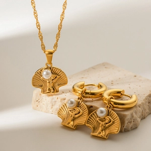 Detail of gold shell earrings and necklace set with pearl and female figure relief