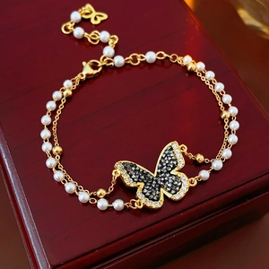 Macro shot of double-layer gold butterfly bracelet with pearls and inlaid rhinestones