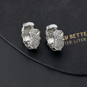 Dettaglio macro di orecchini a cerchio argento con zirconi pavé e design a croce