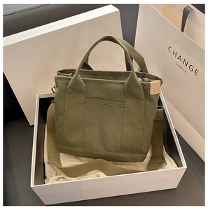 Dettaglio della borsa tote in tela verde con tracolla in una scatola regalo bianca